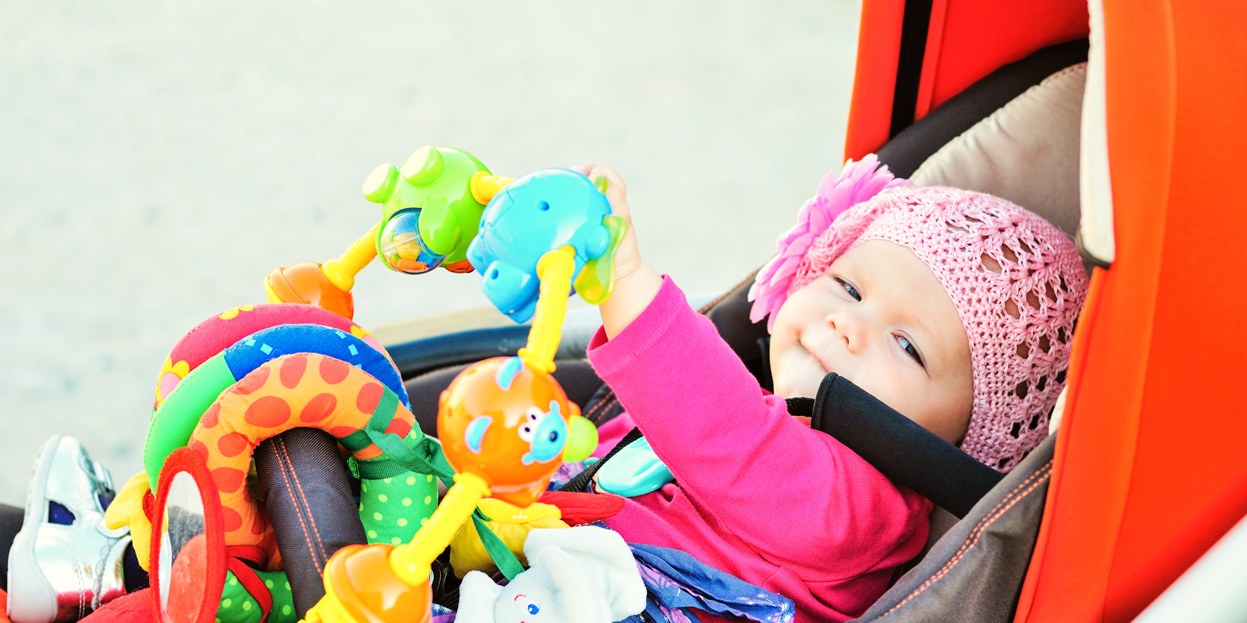 happy baby in the stroller playing toys; Courtesy of Elena Stepanova/Shutterstock